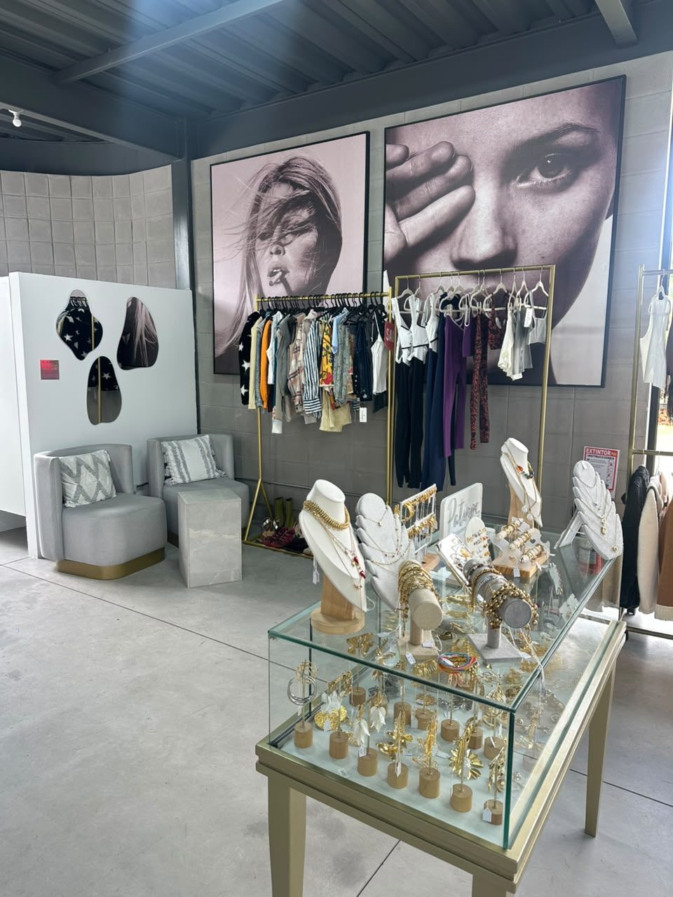 Vitrina de joyas de Patinpe en el centro del local, con perchas de ropa y dos retratos fotográficos en blanco y negro de gran formato al fondo