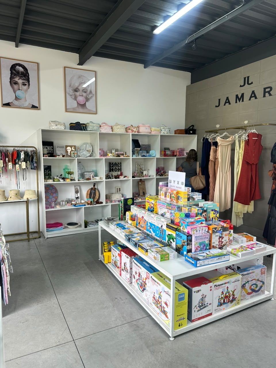 Mesa de juegos y juguetes de Myxo en el centro del local, con estanterías blancas de accesorios y regalos al fondo